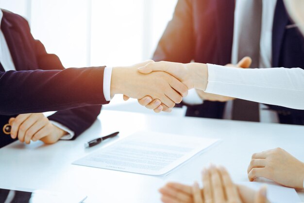 Photo businesspeople or lawyers shaking hands finishing up meeting or negotiation in sunny office. business handshake and partnership.