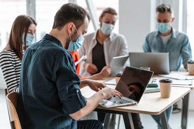 Photo businesspeople meeting at office wearing masks