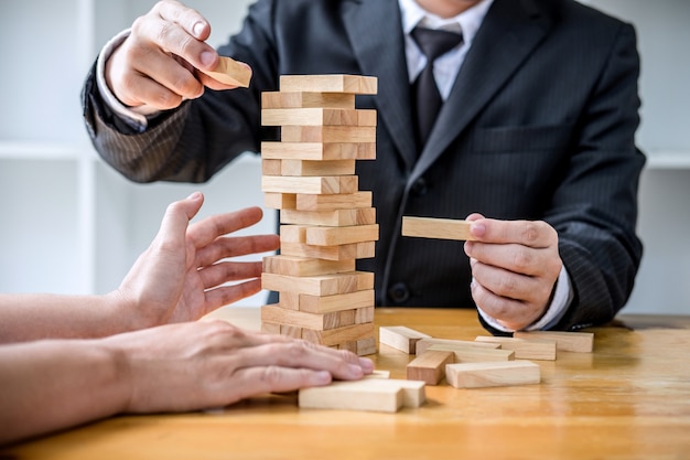 businesspeople placing and pulling wood block on the tower, Alternative risk concept