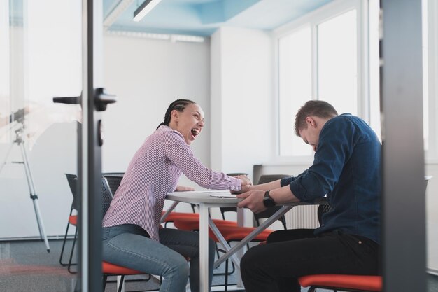 Businesspeople, rivalry and people concept - businesswoman and businessman arm wrestling during corporate meeting in modern bright open space coworking startup business office.