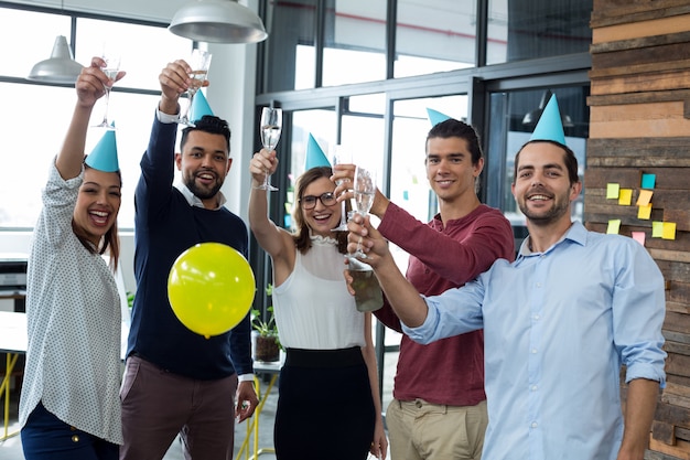 businesspeople showing glasses of champagne in office