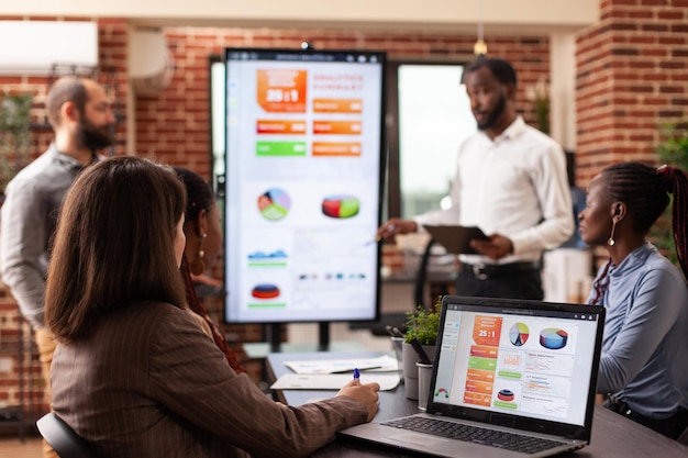 Businesspeople sitting at meeting table in startup company office brainstorming project ideas working at management presentation. Entrepreneurs discussing business strategy at workplace