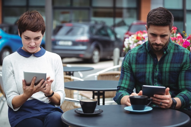 Businesspeople using digital tablet while having coffee