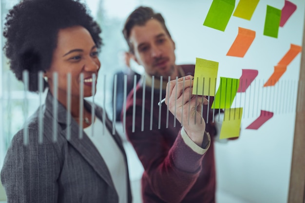 Photo businesspeople using sticky notes against the wall during a brainstorming session