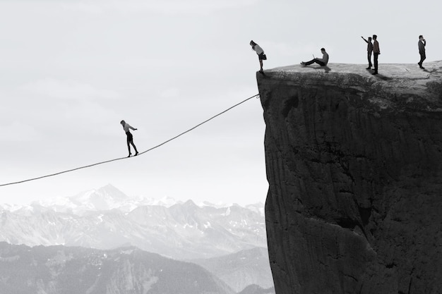 Businesspeople walking on the rope over the cliff