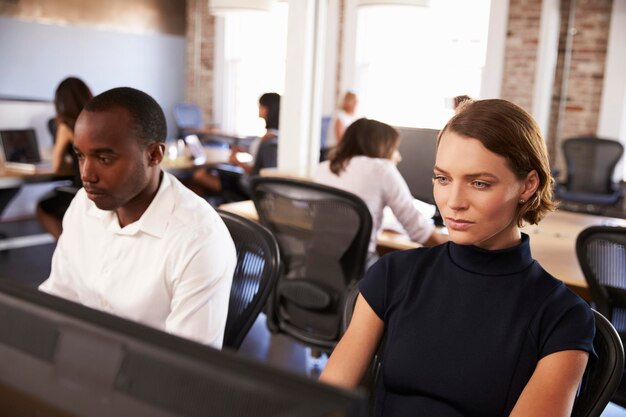 Businesspeople Working At Computers In Busy Modern Office