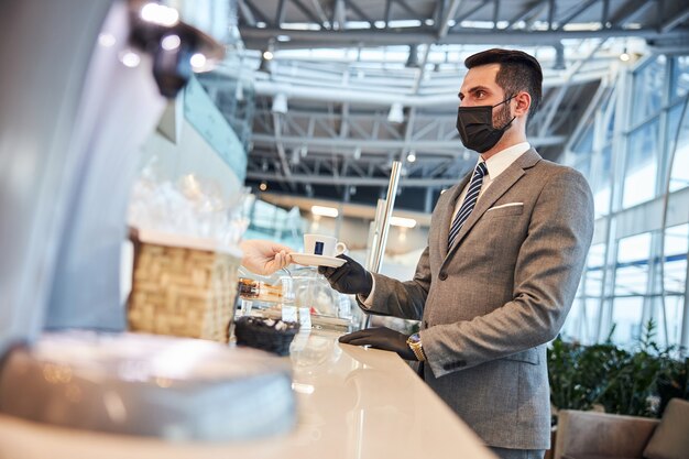 Uomo d'affari che acquista una tazza di caffè al bancone