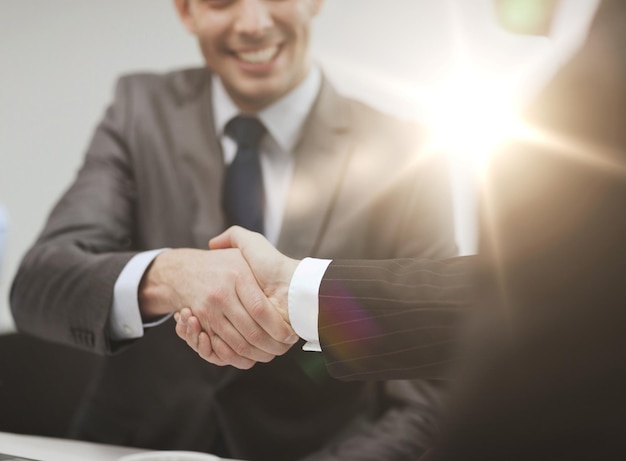 businesss and office concept - two businessmen shaking hands in office