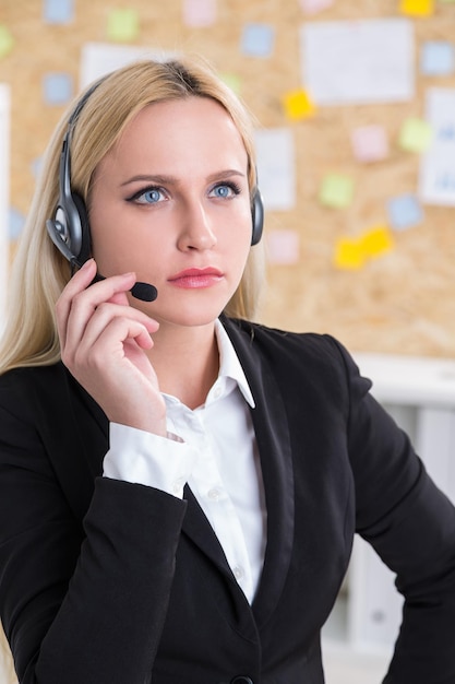 Businesswoman aBusinesswoman in black jacket and headphones with microphone. t work