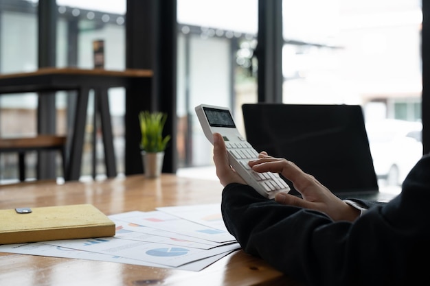 Businesswoman accountant working on desk office with using a calculator to calculate the numbers finance accounting concept