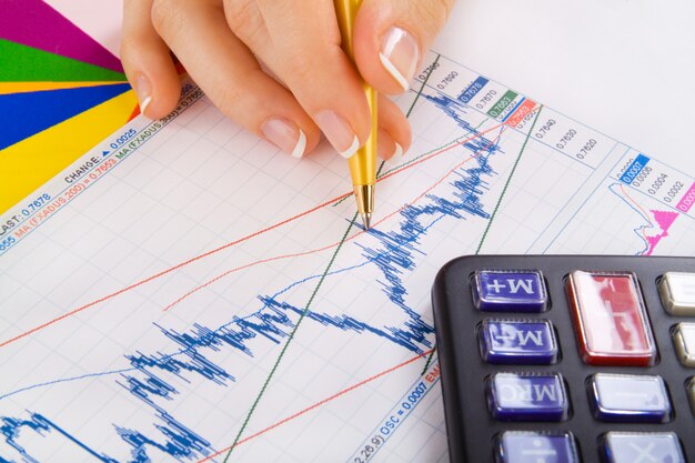 木製の机で電卓で財務報告を分析する実業家