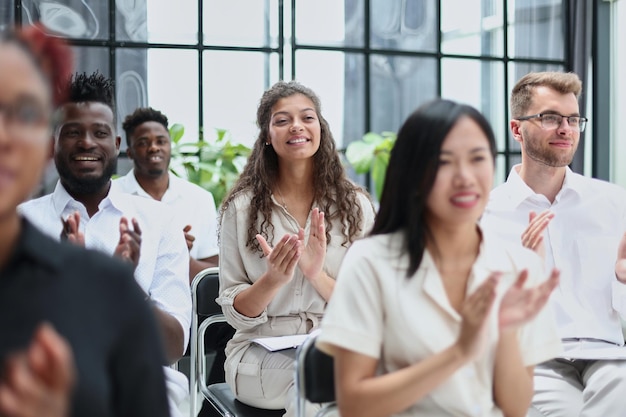 Businesswoman applauding during seminar near interracial colleagues