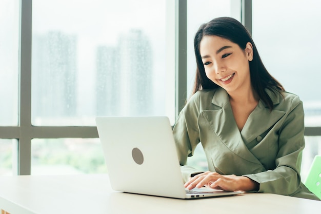 Businesswoman are smile and using computer at window office Trade stock market