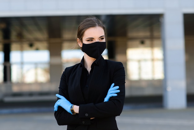 Foto donna di affari in un vestito nero e una mascherina medica nera