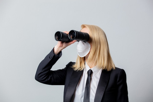 Businesswoman in black suit and face mask with binoculars