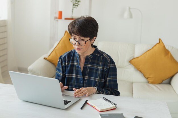 自宅に座ってラップトップ コンピューターで作業し、ho を介して彼女のビジネスを管理する実業家またはブロガー