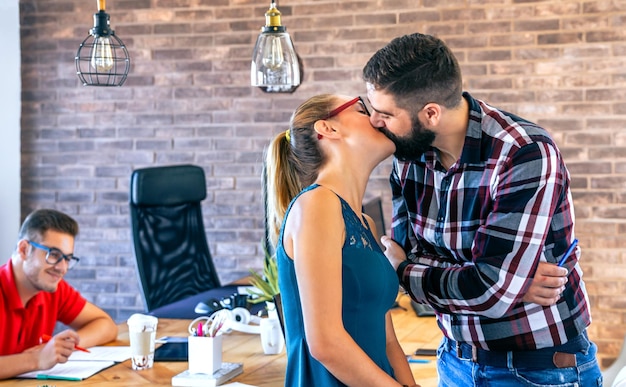 Деловая женщина и бизнесмен целуются в офисе