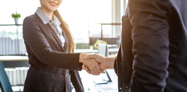 Businesswoman and businessman shaking hands at In the office room background after the contract is signed or handshake greeting deal,business expressed confidence embolden and successful concept