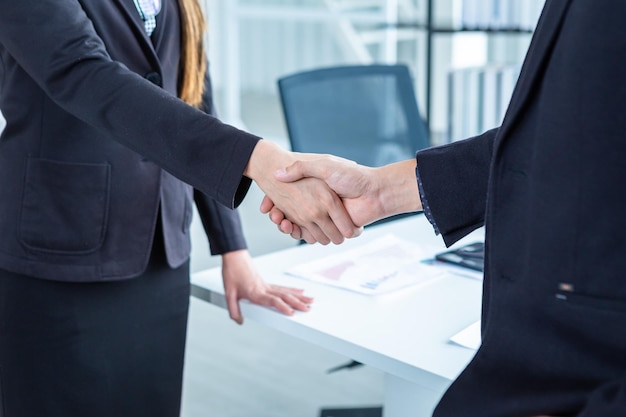 Businesswoman and businessman shaking hands at In the office room background after the contract is signed or handshake greeting dealbusiness expressed confidence embolden and successful concept