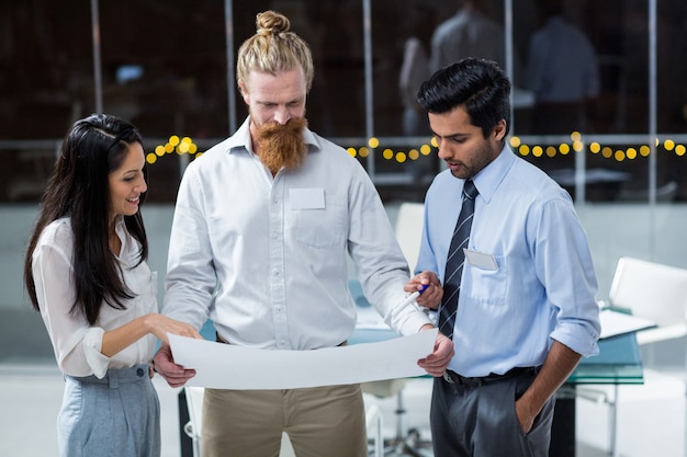 Businesswoman and businessmen discussing over blueprint