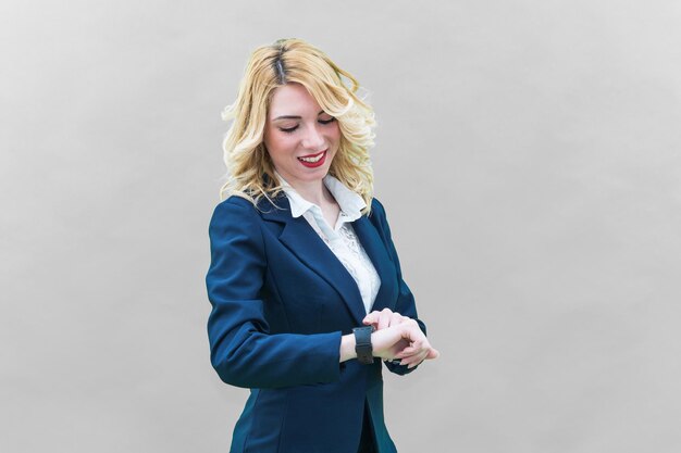 Businesswoman checking time while standing against gray background