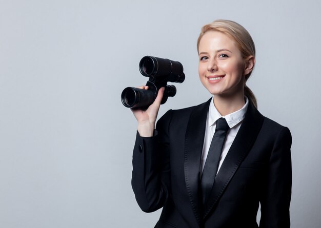 Businesswoman in a classic black business suit with binoculars