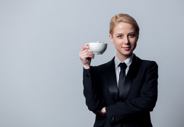 Businesswoman in a classic black business suit with cup of coffee