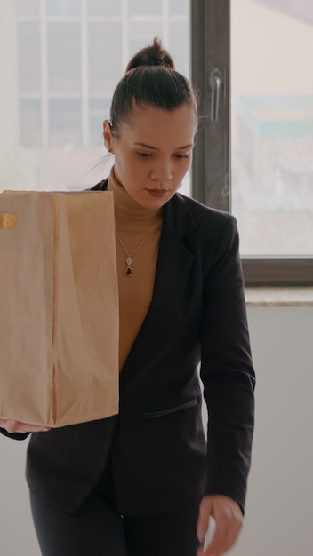 Businesswoman climbing stairs in startup company office hoding takeaway food meal bag during takeout...