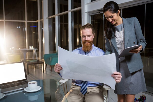 Businesswoman and colleague discussing over blueprint