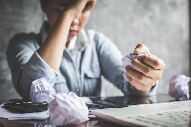 Businesswoman crumpling papers while sitting at desk in office