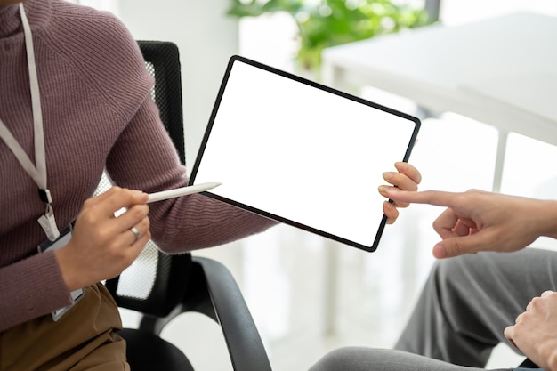 A businesswoman discussing and showing some details on a tablet to a male colleague