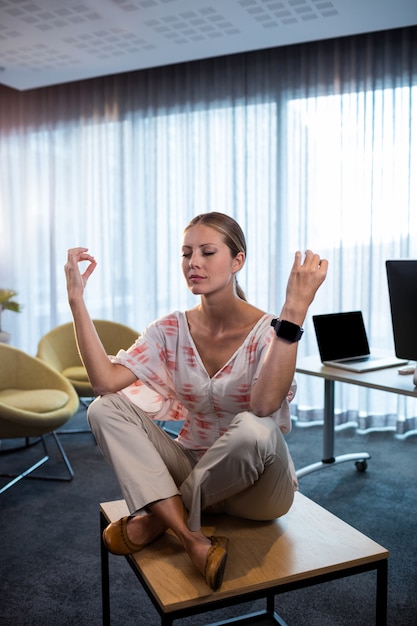 Businesswoman doing yoga with hands in the air