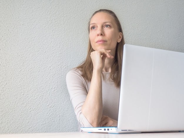 A businesswoman dreams while sitting at her laptop