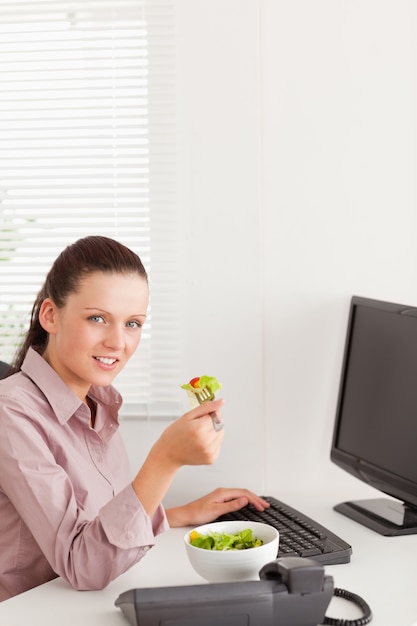 Businesswoman eats salad in her office