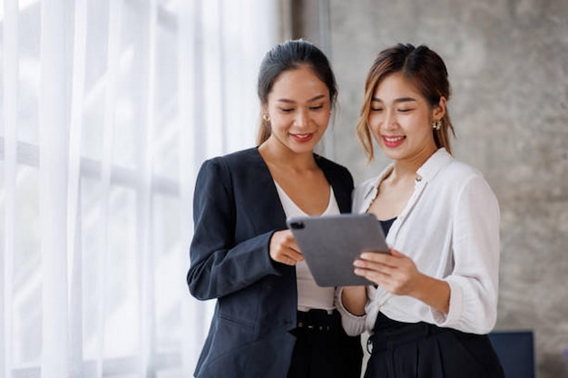 businesswoman executive is using a tablet in meeting discussion with another businesswoman or client