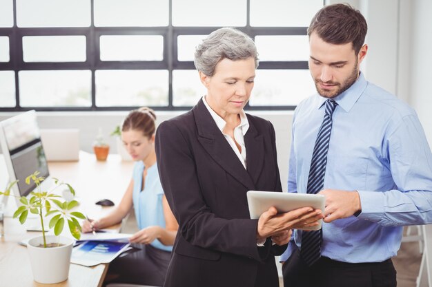 Businesswoman explaining male colleague over digital tablet