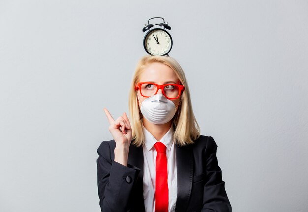 Businesswoman in face mask and red glasses with alarm clock