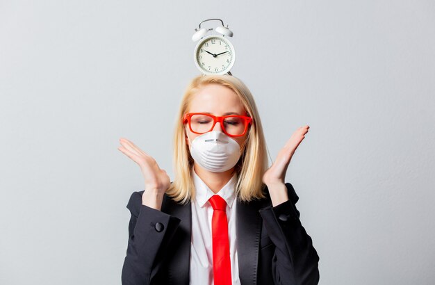 Businesswoman in face mask and red glasses with alarm clock