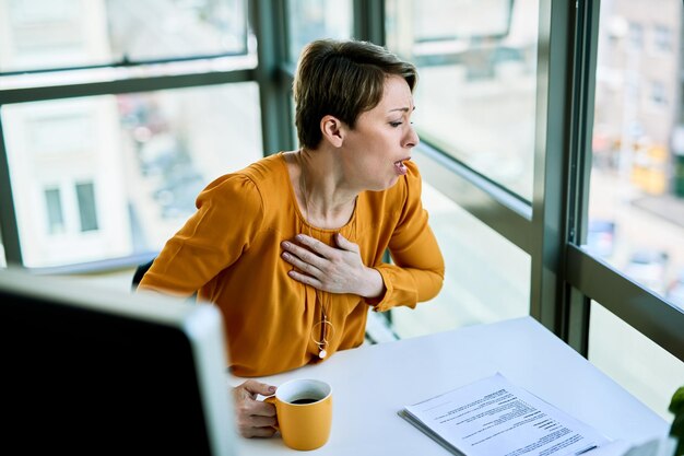 彼女のオフィスの机で働いている間、実業家は病気になり咳をします