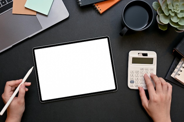 Businesswoman or female financial analysts using calculator and working on tablet