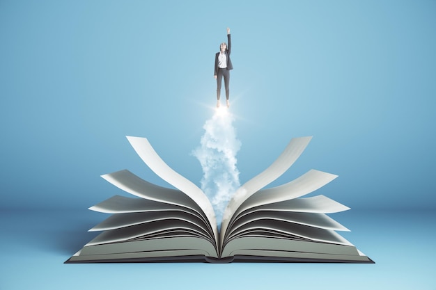 비즈니스 우먼이 파란색 배경에 열린 책 위로 날아갑니다.