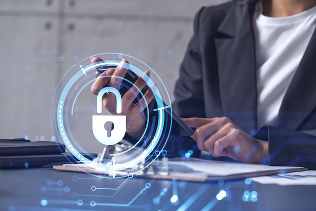 A businesswoman in formal wear checking the phone to sign the contract to prevent probability of risks in cyber security Padlock Hologram icons over the working desk