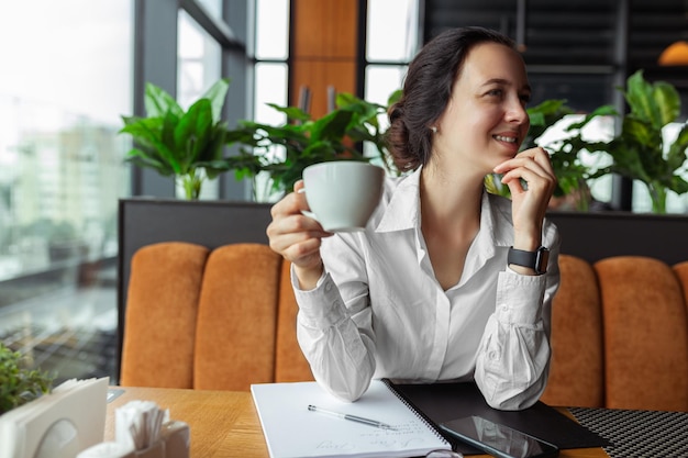 businesswoman in formal wear drinking coffee in cafe while having coffee break