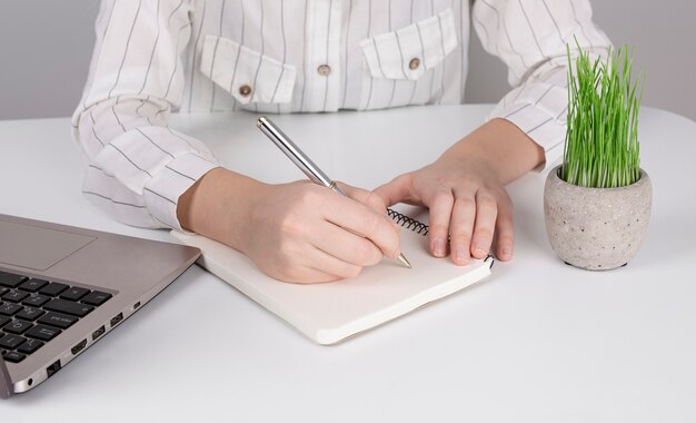 Businesswoman girls hands working in notebook writing down information about desktop home office, near laptop business concept.