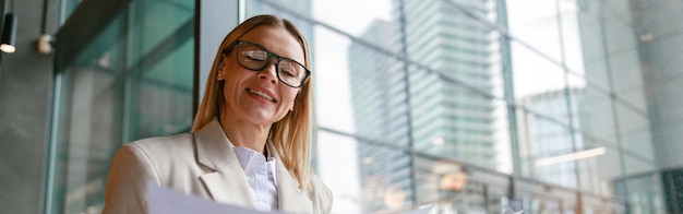 Businesswoman in glasses working with documents and use laptop while sitting in cafe near window