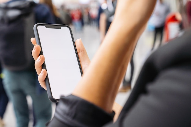 Businesswoman hand holding black cellphone with white screen at\
a trade fair, copyspace for your individual text.