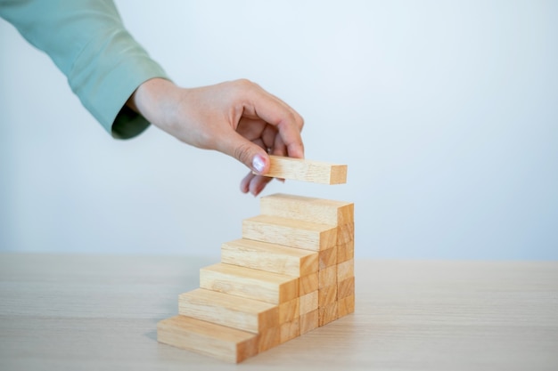 Businesswoman hand holding blocks wood game, Concept Risk of management and strategy business plan.