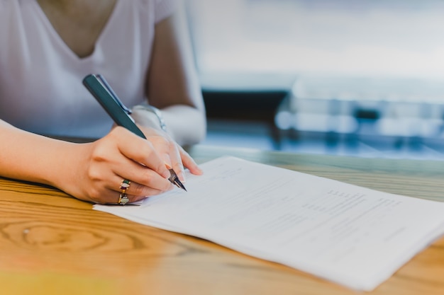 Businesswoman hand signing legal documents financial contract.