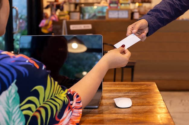 Businesswoman handing out business card to businessman in cafe.