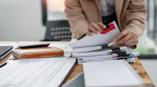 Businesswoman hands working on Stacks paper document files on her desk